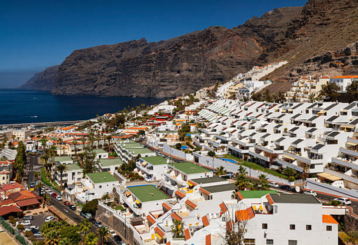 alt="alt="Panoramic view of Los Gigantes in Tenerife, with white terraced buildings and dramatic cliffside by the ocean.""