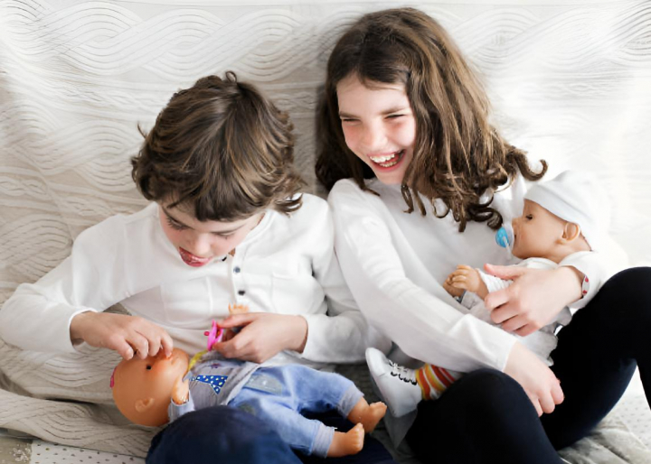 Dos niños jugando con muñecos y riéndose entre ellos