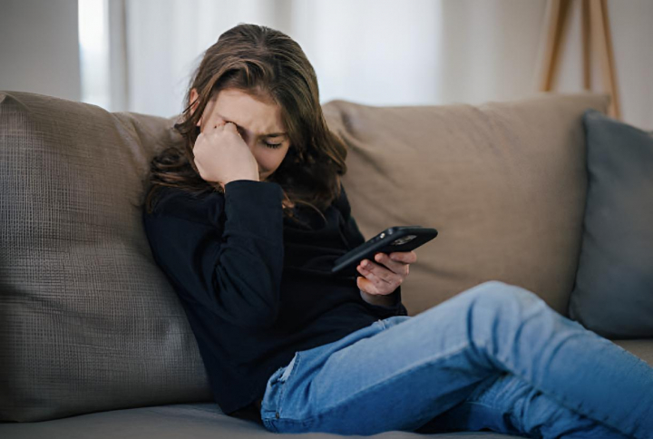 Una niña pequeña llorando por algo que ha visto en su teléfono móvil.