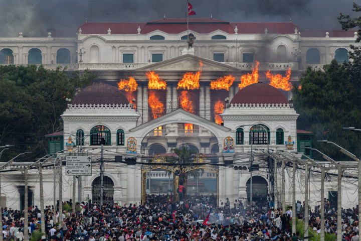 alt="alt="Title: Nepal’s Gen Z Uprising
Credit: © Narendra Shrestha, EPA Images
Caption: Fire and smoke engulf Singha Durbar after protesters stormed and set the government complex alight during violent demonstrations. Kathmandu, Nepal, 9 September 2025.
Story: A government ban of 26 social media platforms on 4 September 2025 was the breaking point for Nepal’s youth. On 8 September, thousands took to the streets, part of a generation of young people around the world refusing to accept systems that perpetuate corruption, unemployment, and economic hardship. Within two days, 76 people were dead, most of them young demonstrators killed by police. Thousands more were injured. On 9 September, following Prime Minister KP Sharma Oli’s resignation, protesters stormed and set fire to Singha Durbar, the historic complex at the heart of Nepal’s government.""