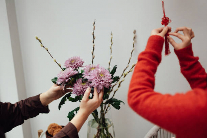 alt="alt="Cropped shot of Asian mother and daughter decorating home with flowers arrangement and traditional Chinese decoration for Chinese New Year. Wishing for a lucky and prosperous new year.""