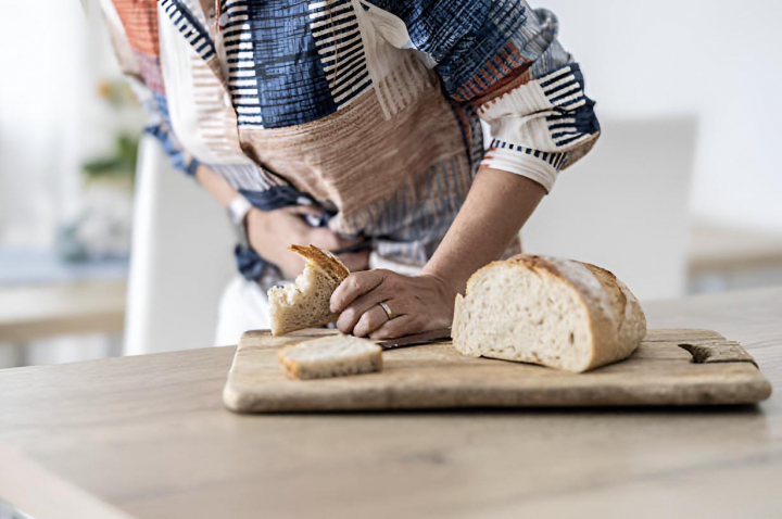 Una joven se sujeta el estómago ante una rebanada de pan fresco que ha probado y le ha sentado mal.