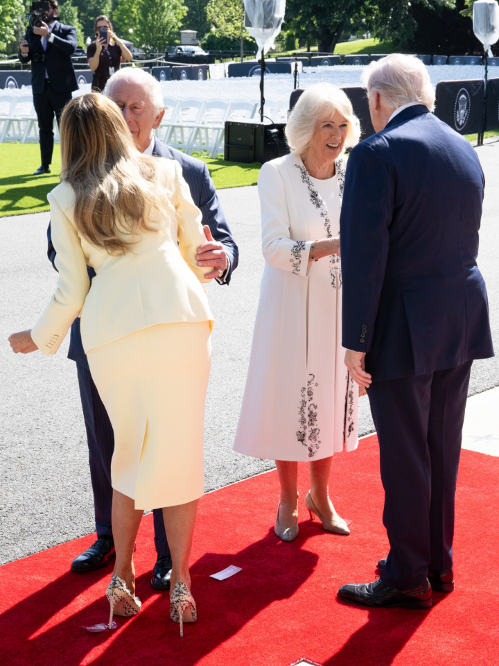 Los reyes Carlos y Camilla y los Trump saludándose en la Casa Blanca con letreros en el suelo para saber dónde colocarse