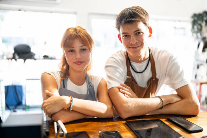 alt="alt="Portrait of a Caucasian female and male teenagers, working at the modern coffee shop or an fast food restaurant""