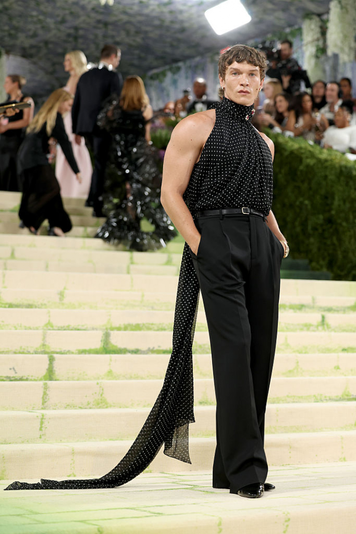 alt="alt="El protagonista de 'Heated Rivalry' eligió un pantalón de traje con una blusa de lunares con una enorme lazada para su primer Met.""