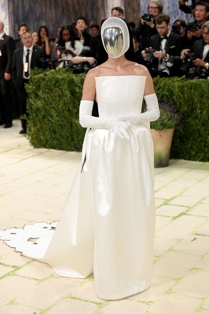 alt="alt="Siempre con espacio para la sorpresa, la cantante apareció con un vestido palabra de honor blanco que combinó con guantes de ópera y una máscara que tapaba su rostro.""
