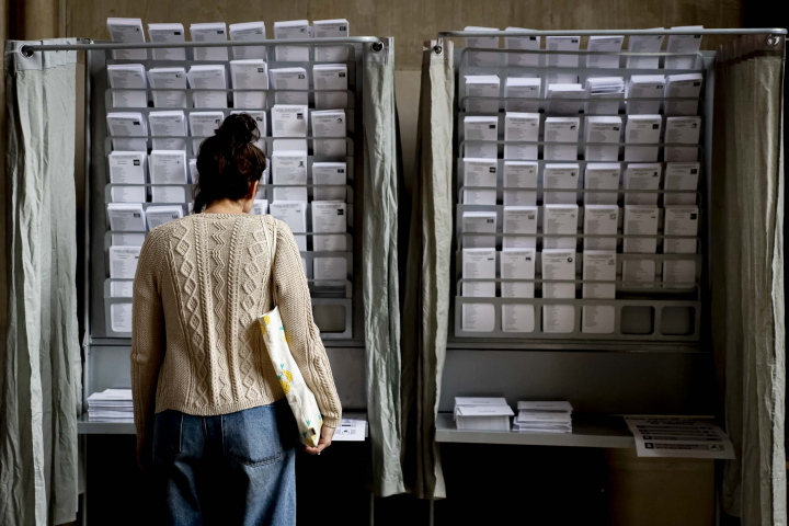 Una mujer frente a las papeletas un día electoral.