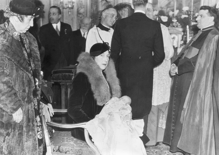 La reina Victoria Eugenia sostiene en brazos a su nieto, el rey Juan Carlos, en su bautizo en Roma, oficiado por el que sería papa Pío XII