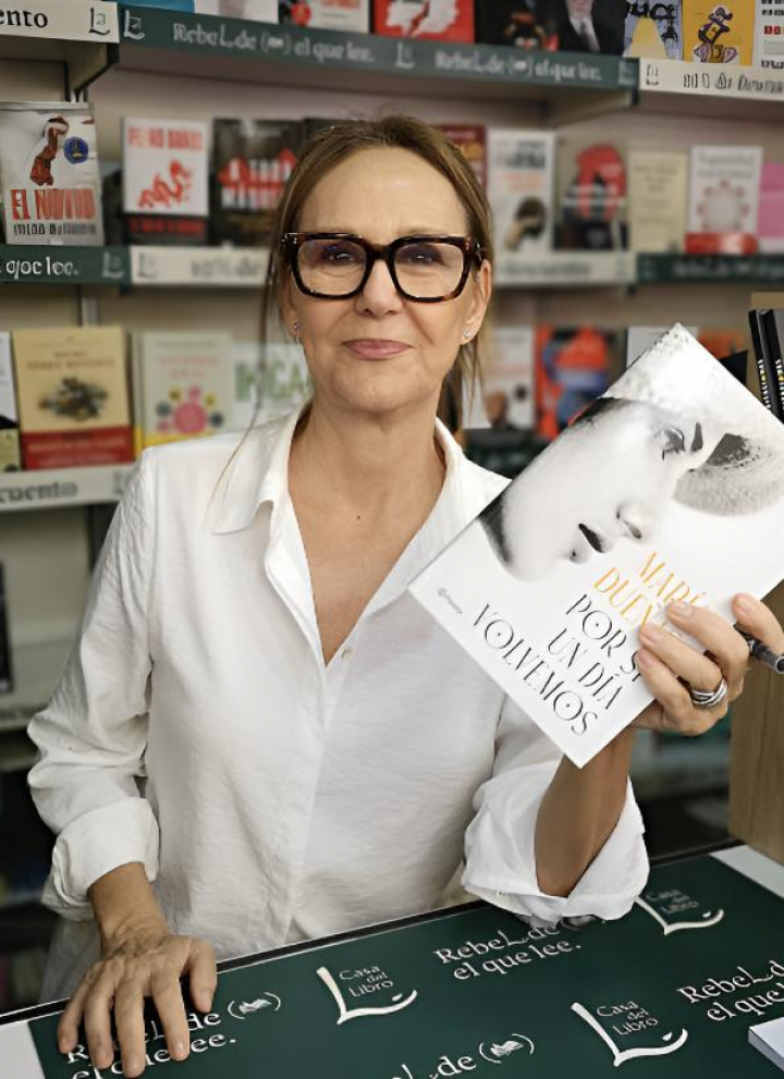 alt="alt="La escritora María Dueñas junto a un ejemplar suyo en la Feria del Libro""