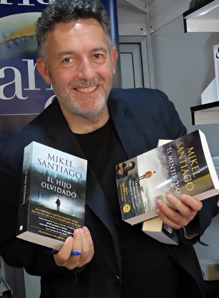 alt="alt="El escritor Mikel Santiago posando con dos de sus libros""