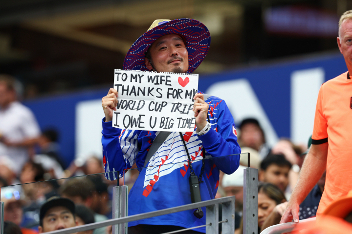 alt="alt="Aficionado japonés con un letrero agradeciendo a su esposa por regalarle el viaje al Mundial 2026.""