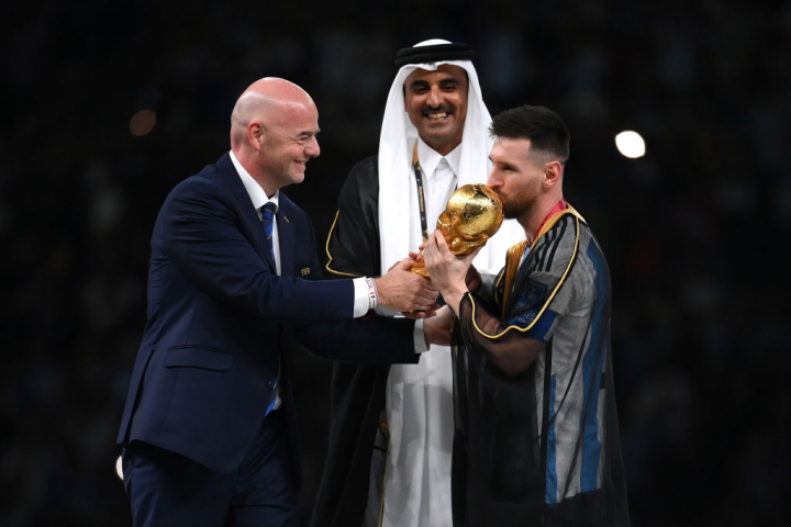 LUSAIL CITY, QATAR - DECEMBER 18: Lionel Messi of Argentina kisses the trophy as he is presented the FIFA World Cup Qatar 2022 Winner's Trophy by Gianni Infantino, President of FIFA, while Sheikh Tamim bin Hamad Al Thani, Emir of Qatar, watches at the award ceremony following  the FIFA World Cup Qatar 2022 Final match between Argentina and France at Lusail Stadium on December 18, 2022 in Lusail City, Qatar. (Photo by Shaun Botterill - FIFA/FIFA via Getty Images)