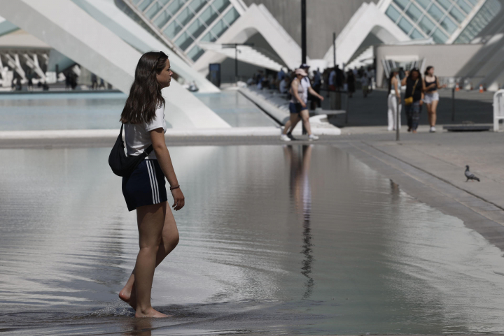 Una joven se refresca en el estanque de la Ciudad de las Artes y las Ciencias de Valencia.