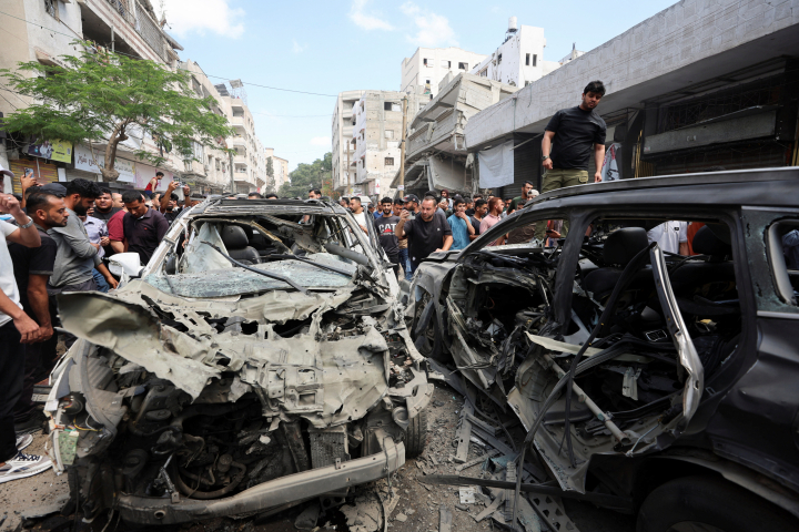 Un grupo de palestinos inspeccionan los restos de dos vehículos bombardeados por Israel, ataque que ha asesinado a una adolescente de 16 años que iba al instituto.
