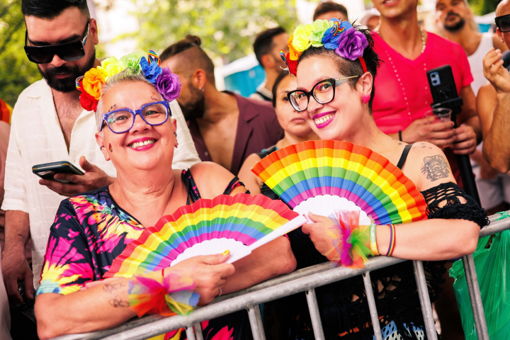 Dos participantes con abanicos arcoiris durante la celebración del Orgullo LGTBIQ+ en Madrid