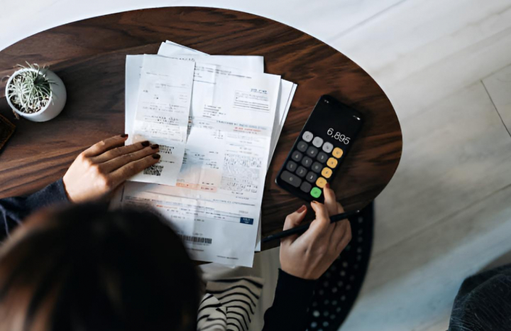 Una mujer organizando sus facturas y calculando cuánto tiene que pagar