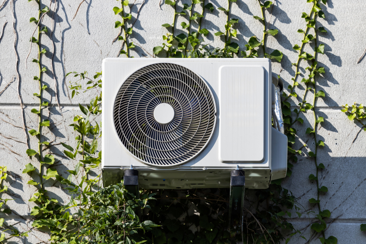 Un aparatos de aire acondicionado por encima de unas plantas