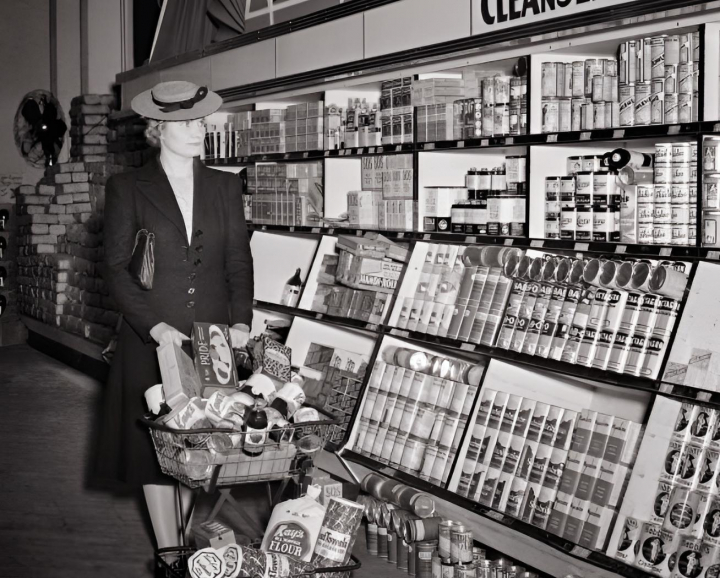 alt="alt="Una mujer empuja un carrito de la compra lleno de alimentos en un supermercado en la década de 1940.""