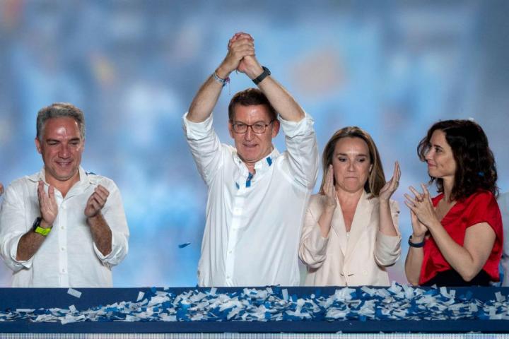 Ayuso, de rojo, mira a Feijóo en Génova tras conocer el resultado de las elecciones.