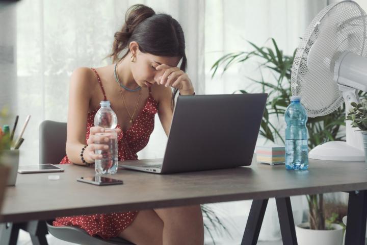 Imagen de archivo de una chica en una jornada de altas temperaturas, mientras mira su portátil.