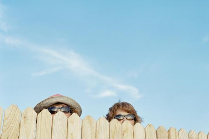 Imagen de dos vecinas observando algo a través de la valla.