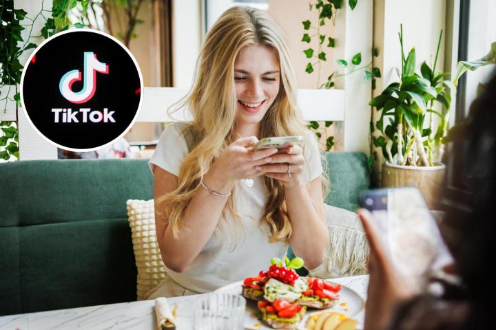 Una chica haciendo una foto a su comida en un restaurante y el logo de TikTok