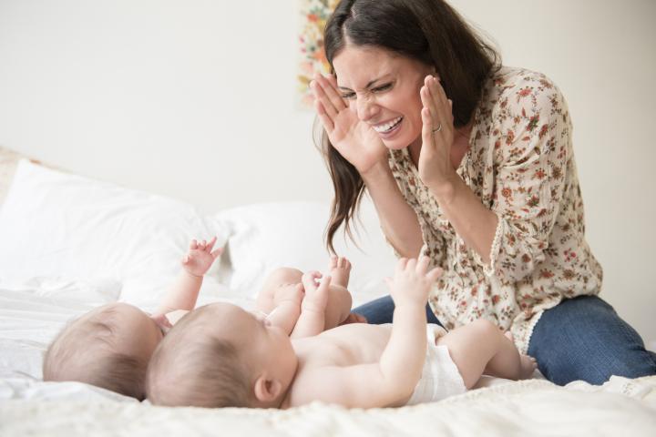 Una mujer jugando al cucú-tras con sus bebés.