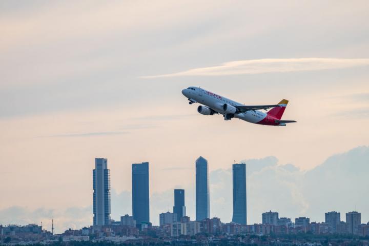 Un vuelo de Iberia despega desde el aeropuerto de Madrid, con las cuatro torres al fondo.
