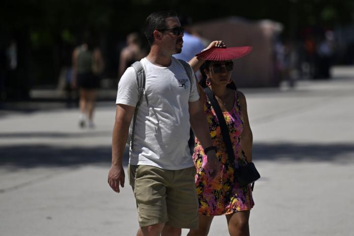 Dos turistas se protegen del calor de finales de junio en Madrid