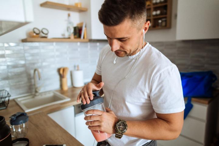 Un hombre se prepara un batido proteínico antes de entrenar.