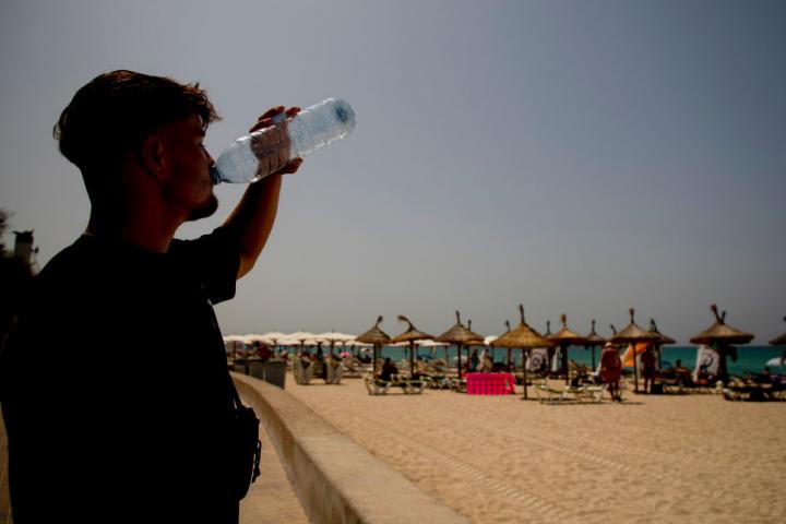 Un joven apura una botella de agua en una playa de Mallorca