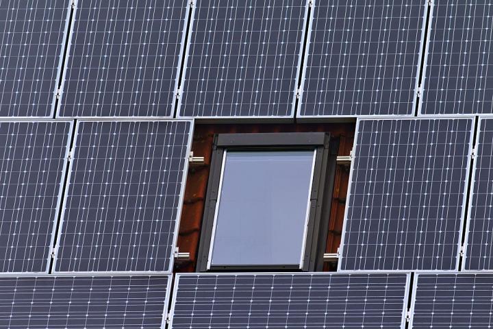Paneles solares instalados en el tejado de una vivienda rodean una ventana.
