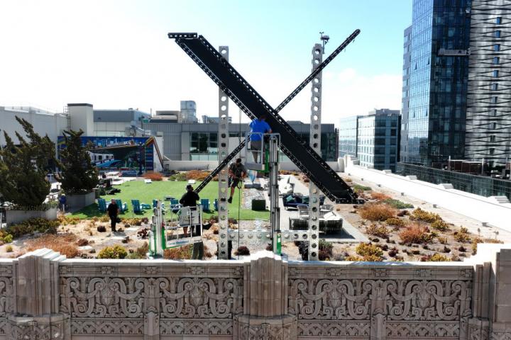 Un grupo de operarios trabaja en el montaje del gran cartel del nuevo logotipo de Twitter.