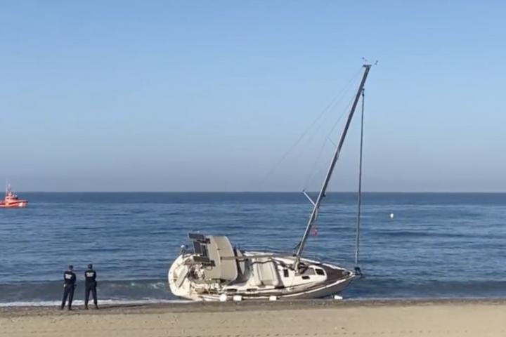 Dos agentes de policía custodian el velero que ha aparecido varado en Almería
