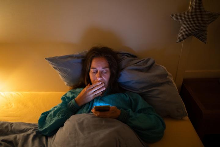 Una joven consulta el teléfono móvil nada más despertarse.