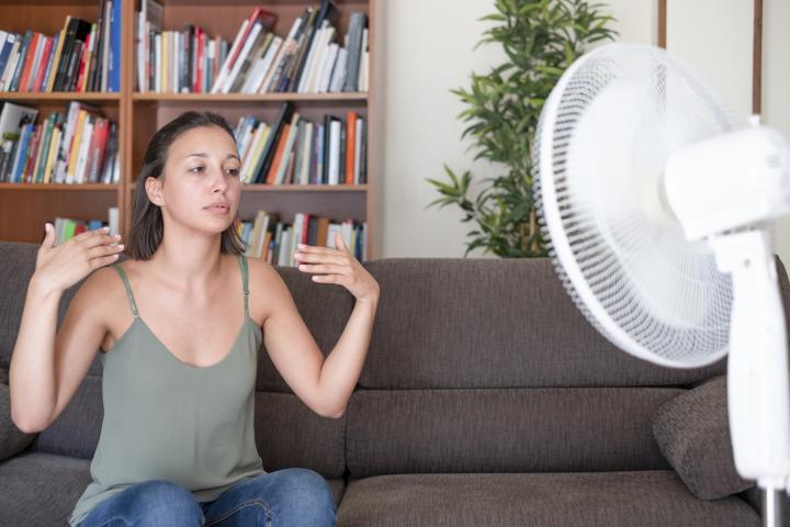 Imagen de archivo de una mujer con un ventilador en su casa.