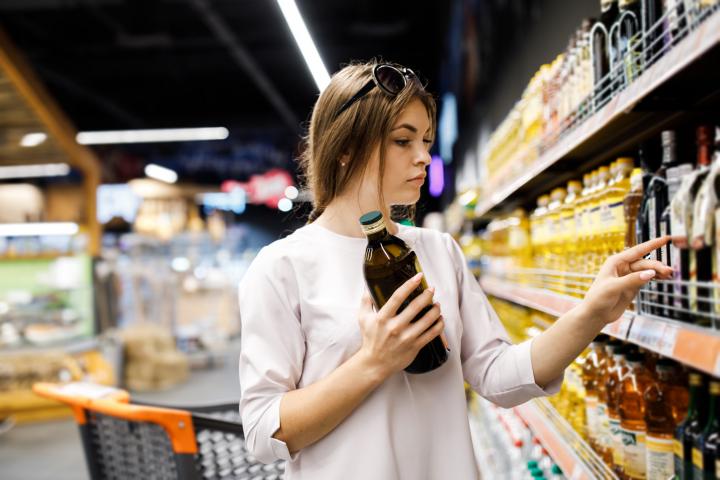 Imagen de archivo de una mujer eligiendo aceite de oliva en un supermercado.