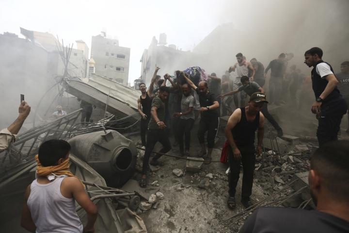 Un grupo de palestinos recoge el cadáver de una persona entre los restos de un edificio destruido por los bombardeos de Israel.