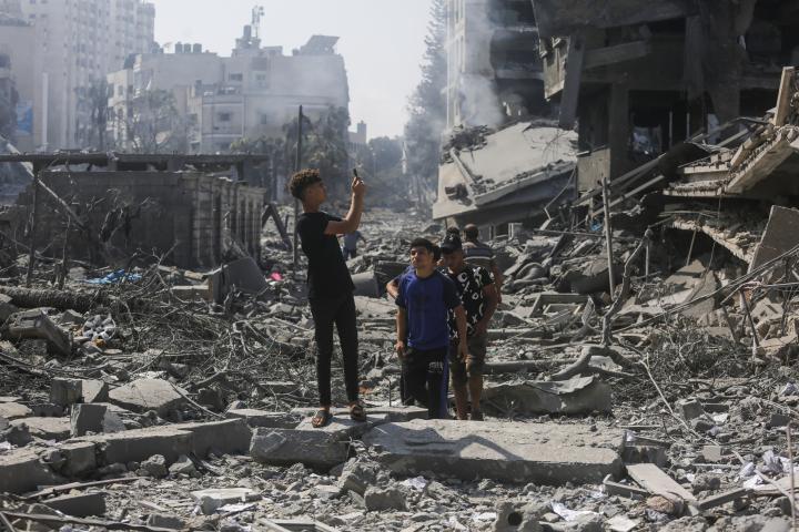 Jóvenes palestinos haciendo una fotografía tras el ataque israelí a un edificio en Gaza.