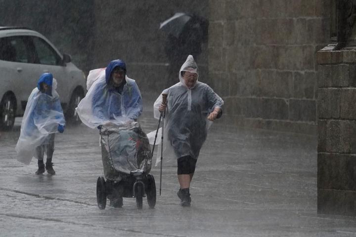 Varias personas caminan con chubasqueros bajo una fuerte tormenta, en una imagen de archivo