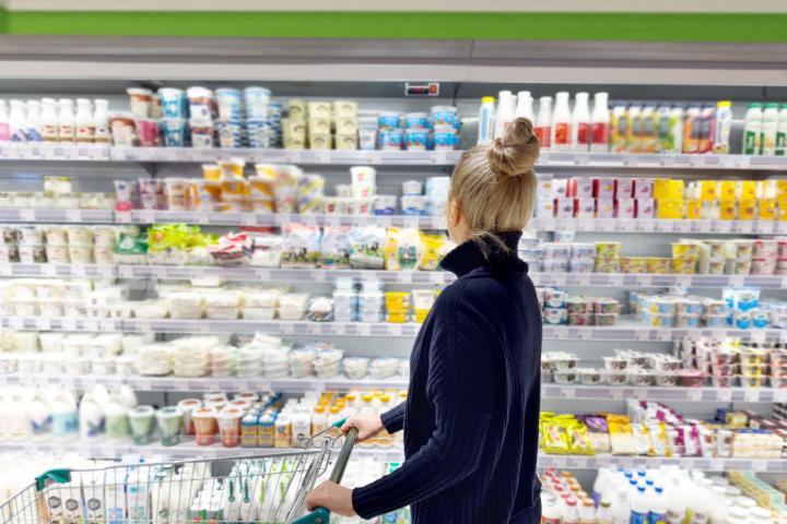 Una mujer eligiendo yogures en un supermercado.