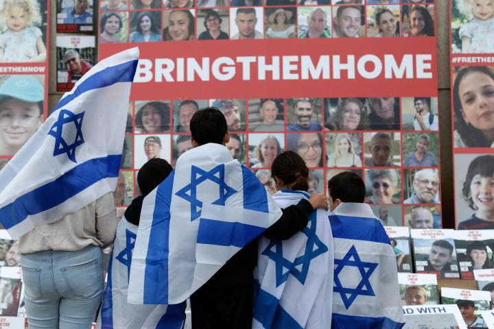 Niños envueltos con la bandera israelí miran los retratos de los civiles secuestrados por Hamás, durante una manifestación en favor de Israel celebrada en la Biblioteca Universitaria Central de Bucarest, el 2 de noviembre.