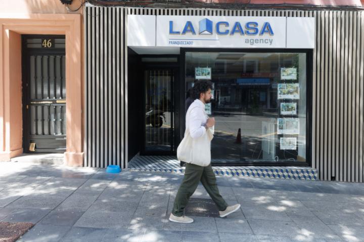 Un joven pasa por delante de una inmobiliaria en Madrid.