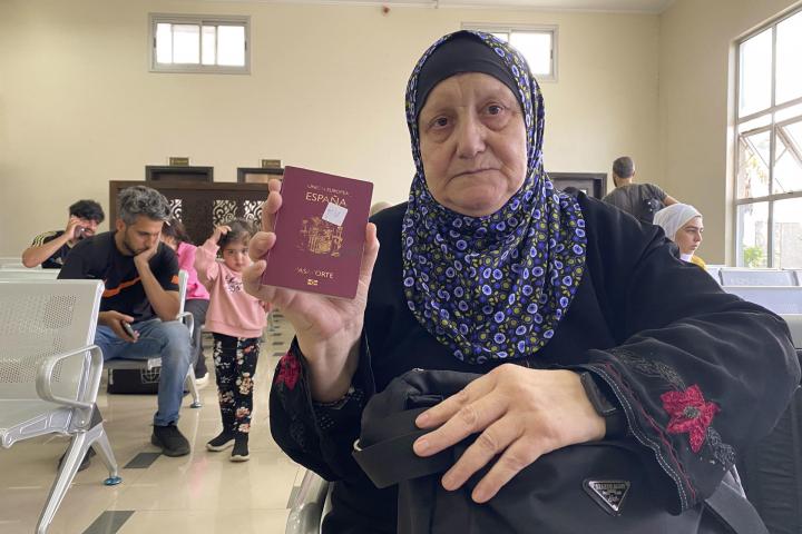 Una mujer muestra su pasaporte español mientras espera a poder salir de Gaza en el paso de Rafah.