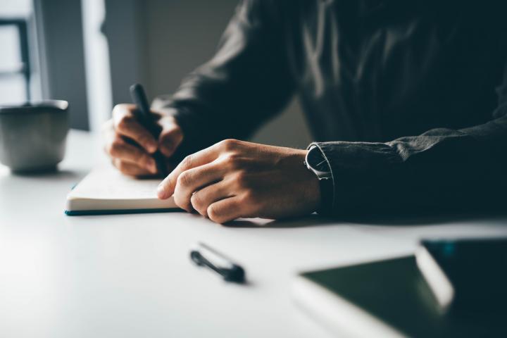 Un hombre escribe en un cuaderno a bolígrafo
