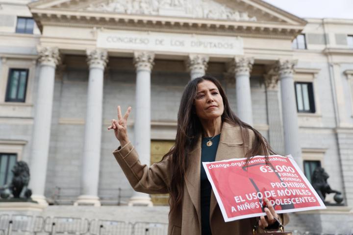Ángela Sánchez Pérez Merino, docente de la comunidad de Madrid, posa frente al Congreso de los Diputados para presentar la lista de firmas recogidas para una campaña de regulación de los teléfonos móviles en menores, que ha organizado junto a otra decente de secundaria, este jueves en Madrid.