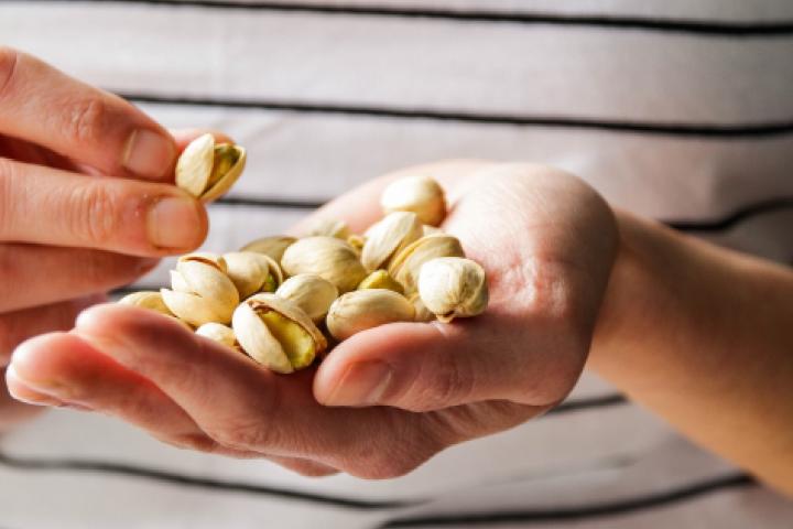 Una persona con un puñado de pistachos en la mano.