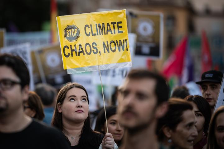 Un joven con una pancarta que pide parar el "caos climático, ya".