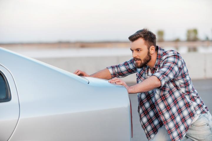 Foto de archivo de un hombre empujando un coche.