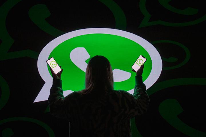 Una mujer, ante el logotipo de WhatsApp proyectado en el suelo.